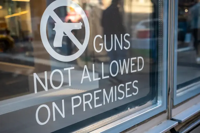 Signage on a window saying "guns not allowed on premises."